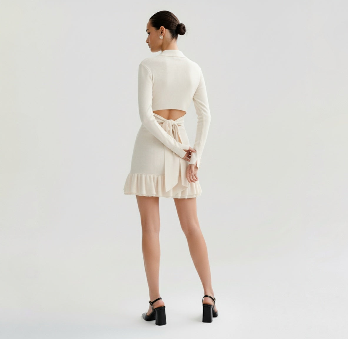 Woman wearing a Ivory dress with long sleeves on a plain background