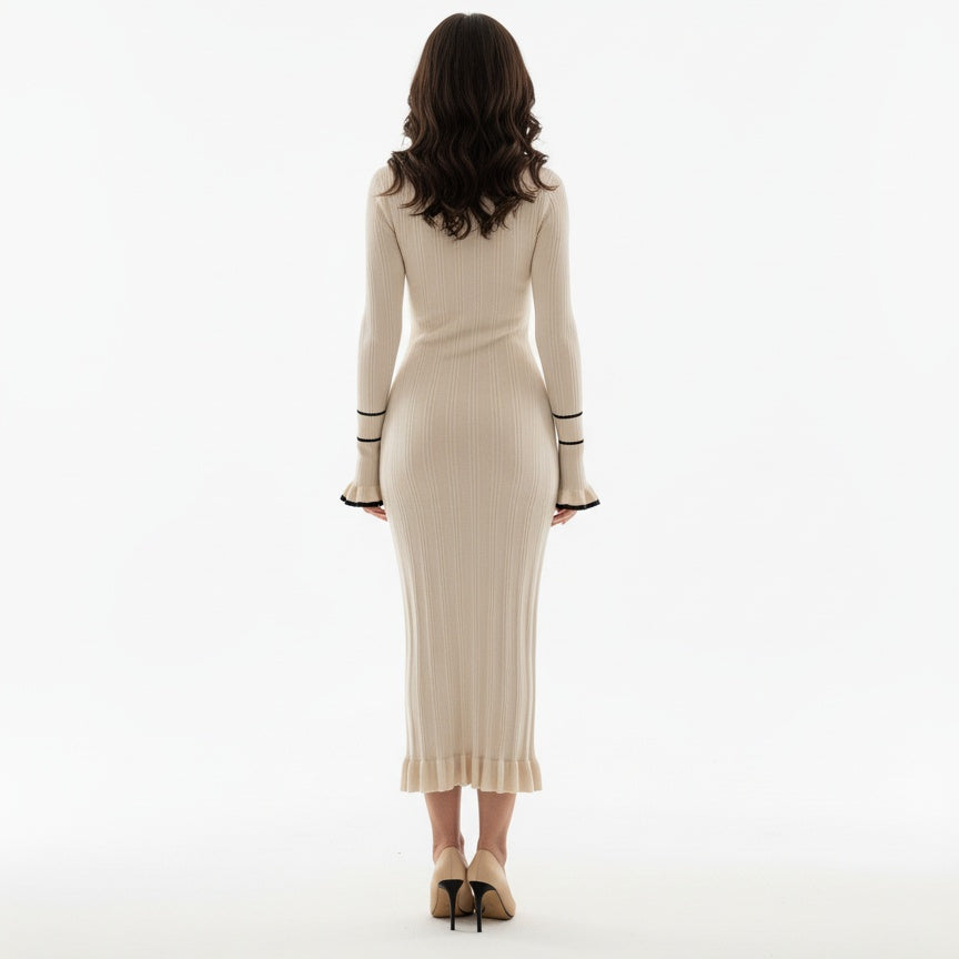 Woman wearing a beige ribbed dress with black cuffs on a white background