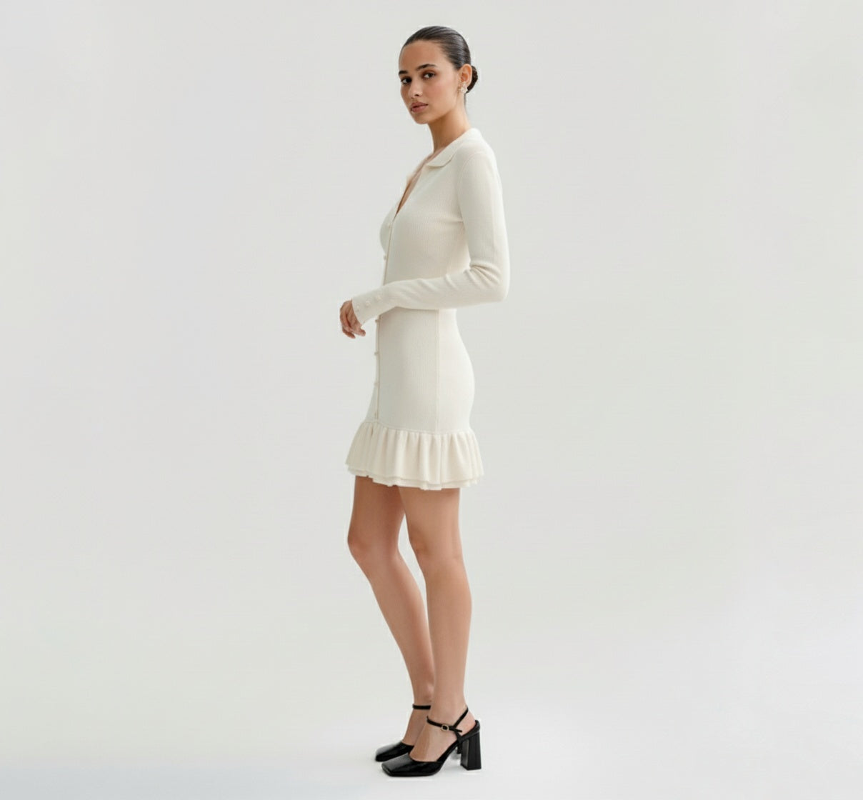 Woman wearing a Ivory dress with long sleeves on a plain background