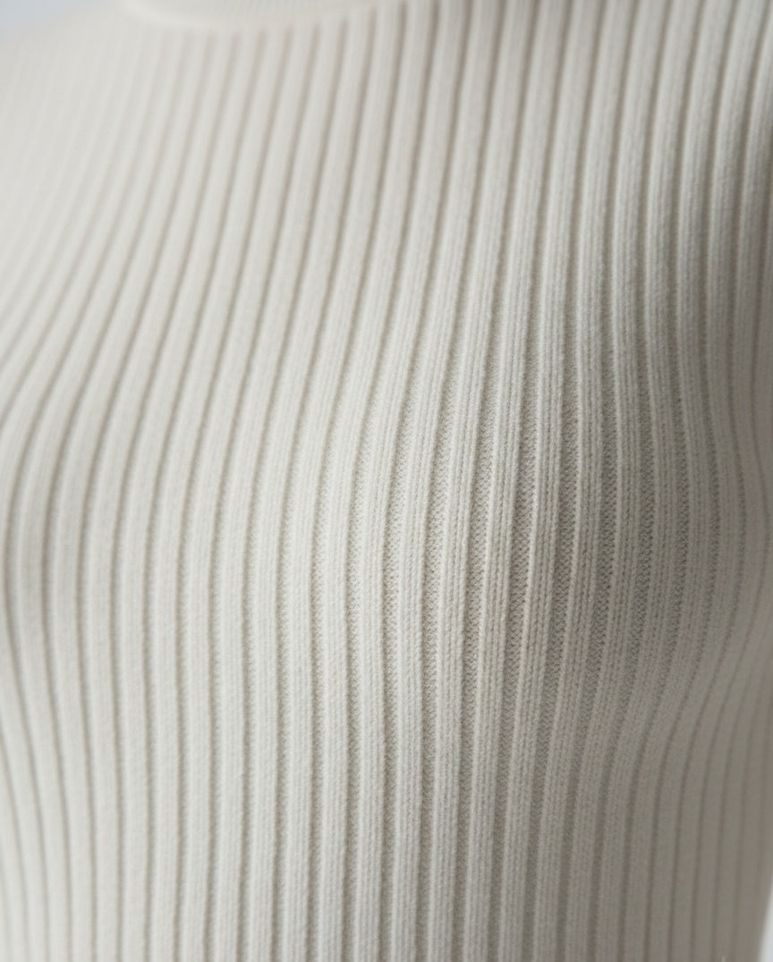 Close-up of the cozy knitted fabric texture of the CELESTE KNITTED MINI DRESS in elegant cream color.